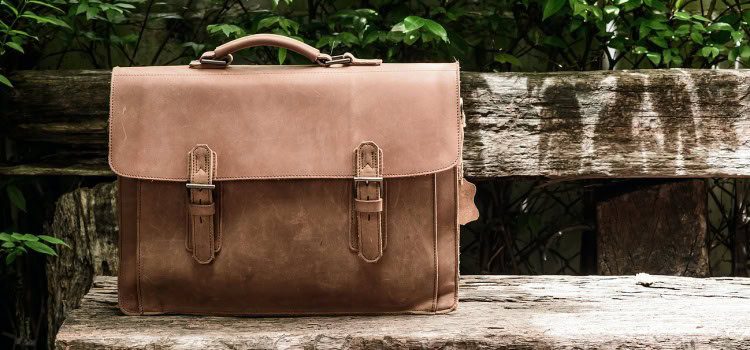 Leather handbag sitting on a wooden bench.