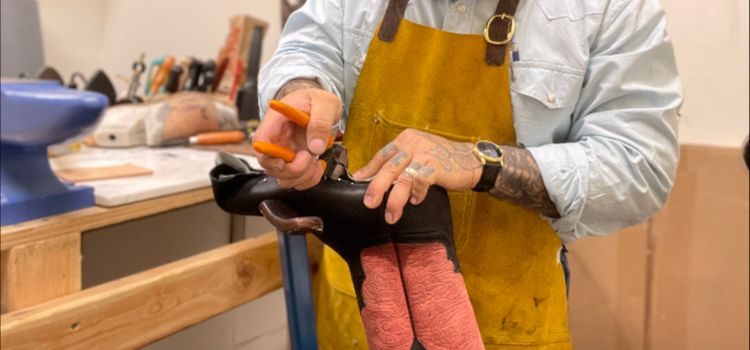 Craftsperson resoling the sole of a pair of cowboy boots