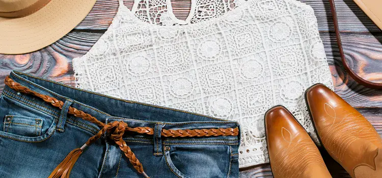 Pair of cowgirl boots and clothing item being prepared for travel.